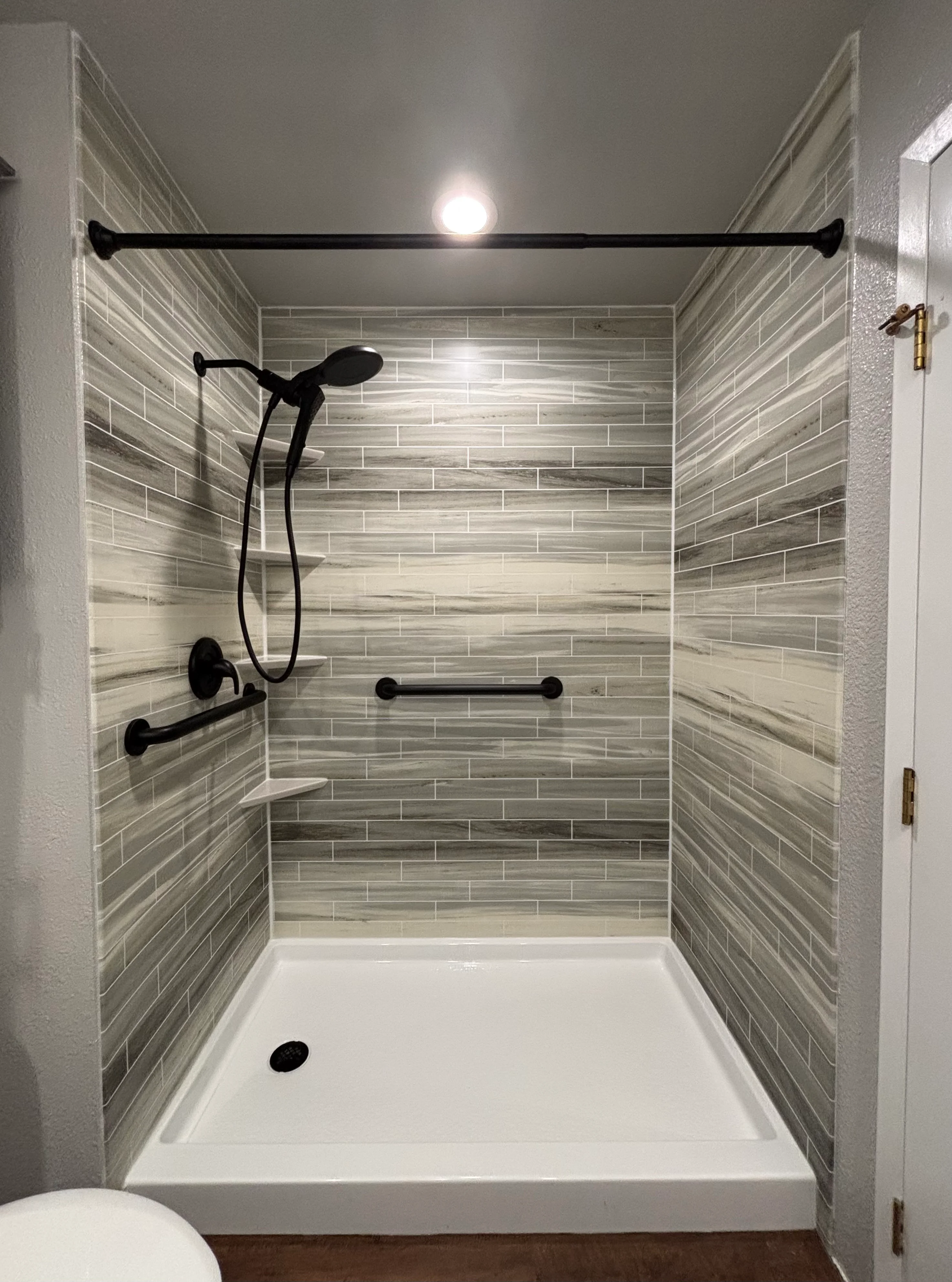 A fully remodeled bathroom in a Tacoma home featuring custom wall tile in the shower, a new vanity, and updated fixtures. The space reflects a clean, modern finish suited to the Pacific Northwest climate.