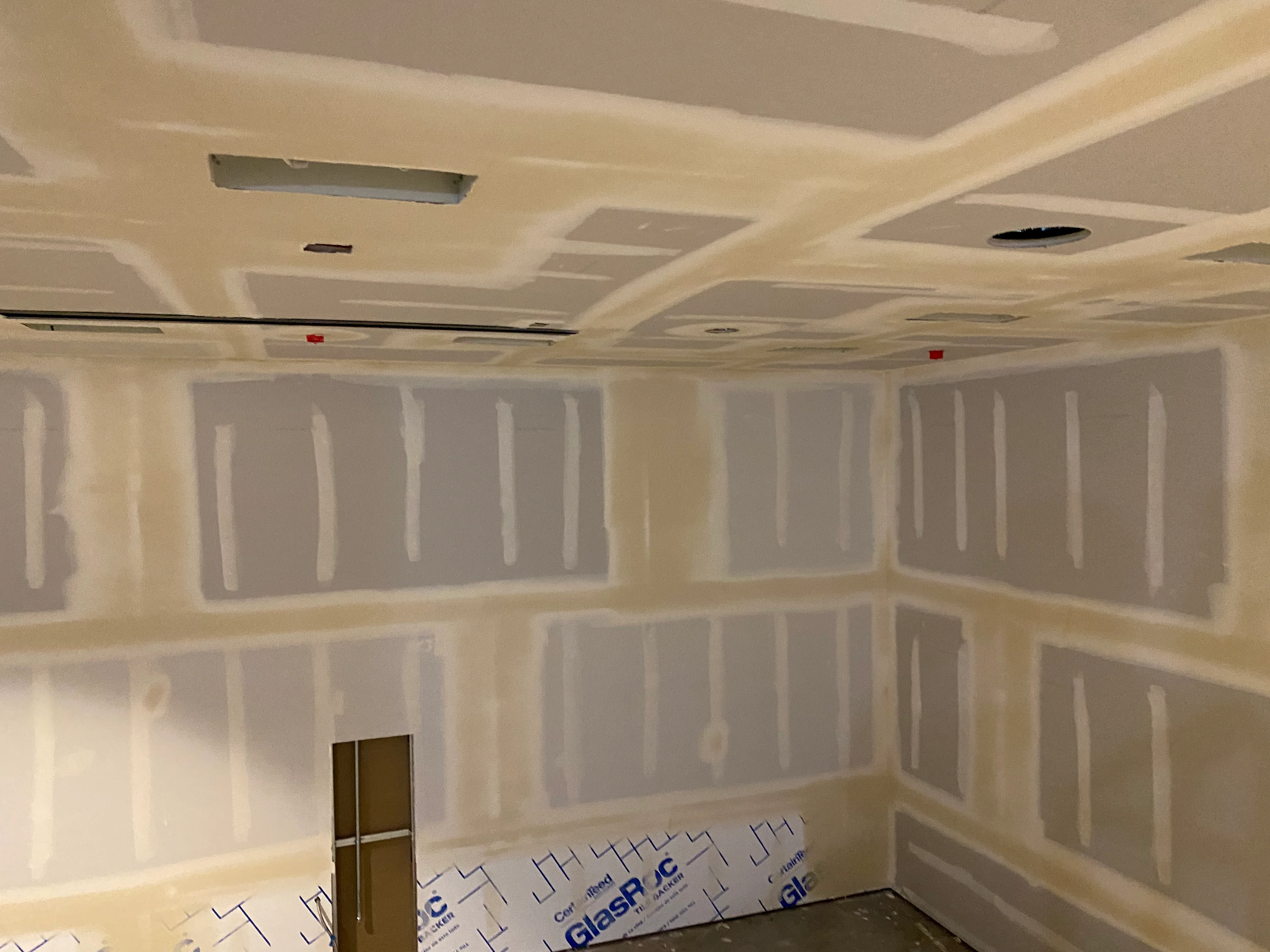 Freshly installed and taped drywall covering the walls and ceiling of a remodeled room in a Tacoma home. The surface is smooth, seams are finished, and the walls are ready for primer and paint.