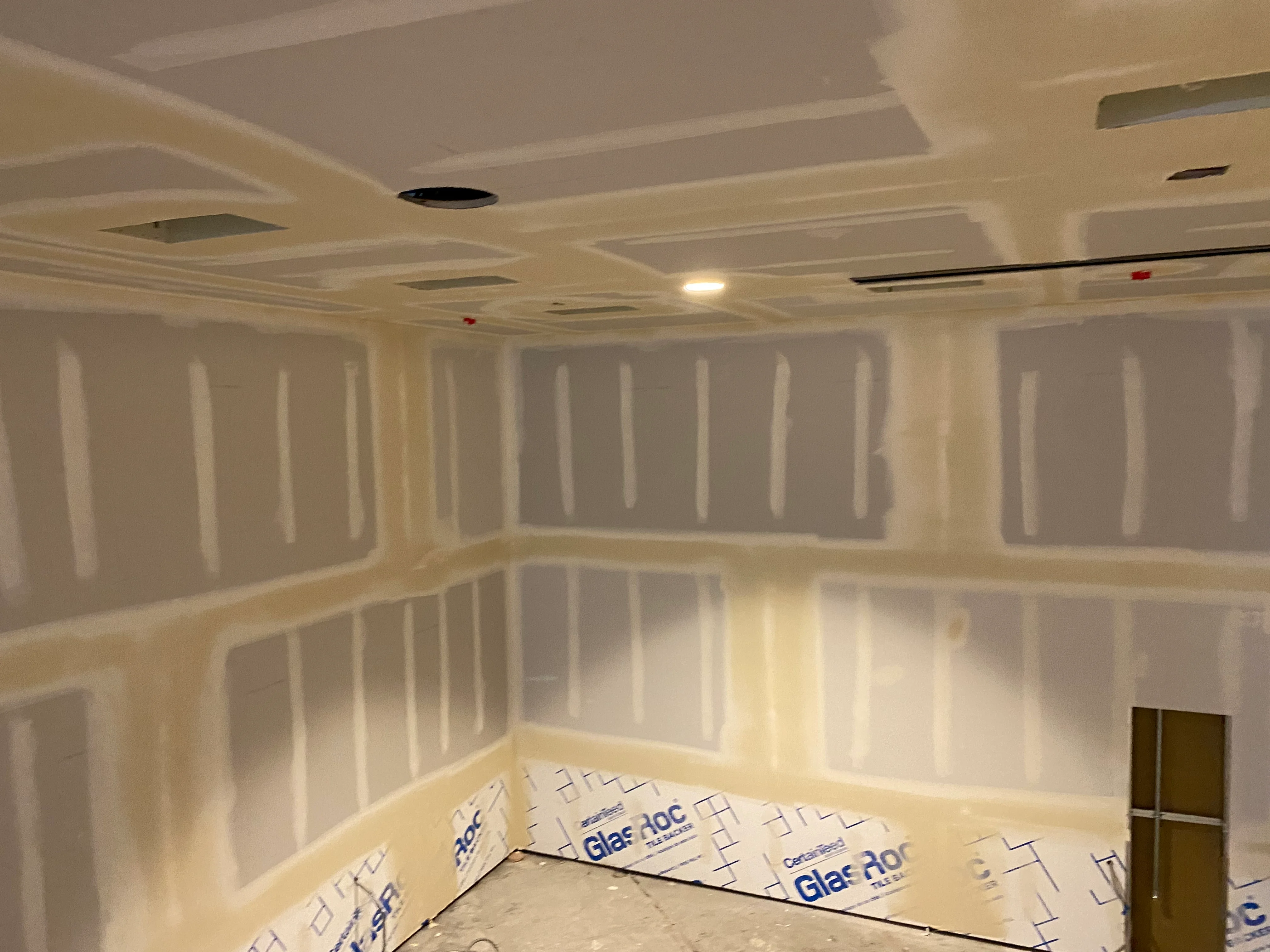 A freshly repaired and texture-matched drywall patch on an interior wall of a Tacoma single-family home, sanded smooth and ready for paint. The repaired area blends seamlessly with the surrounding orange peel wall texture.